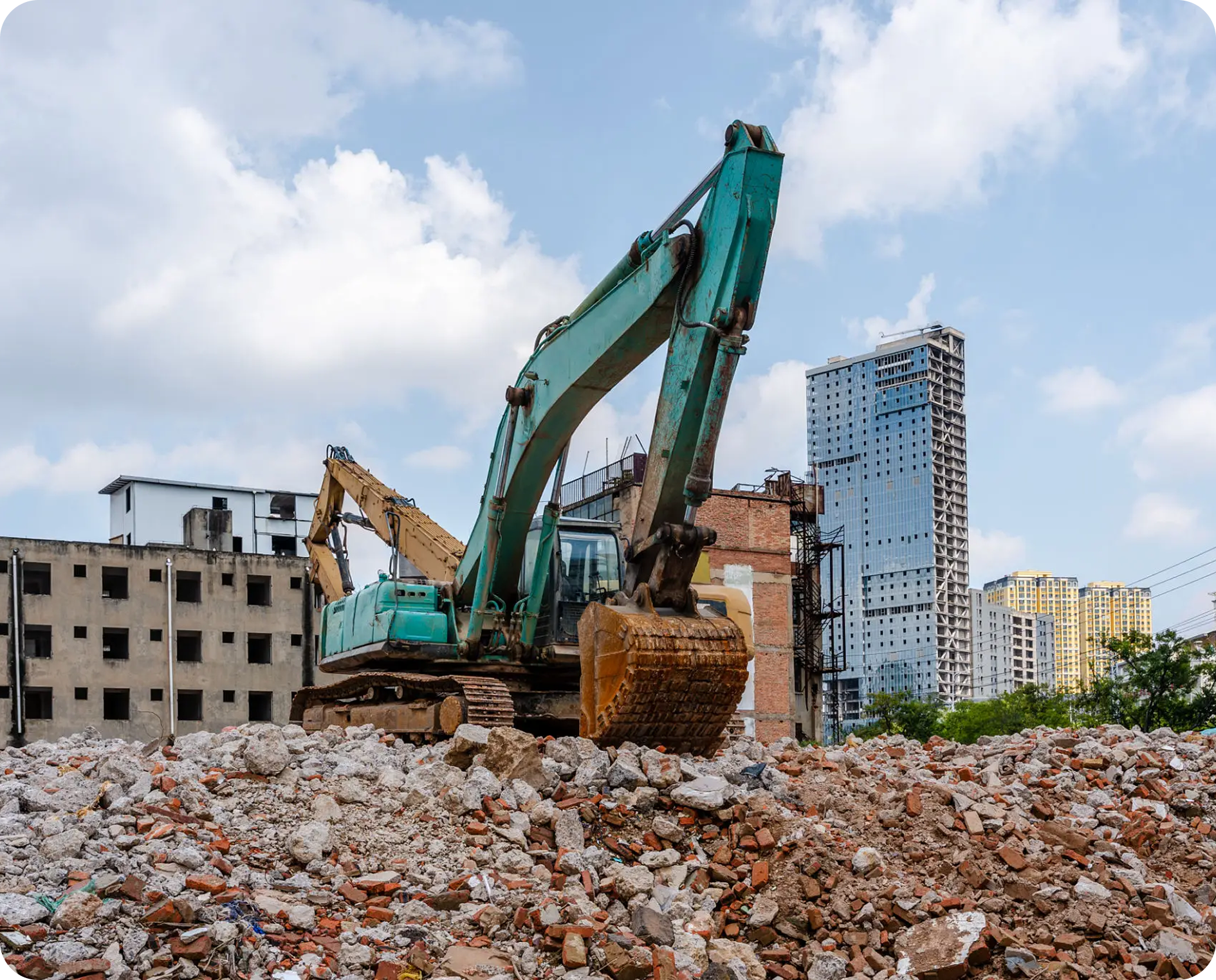 Excavator on rubble with city buildings background.